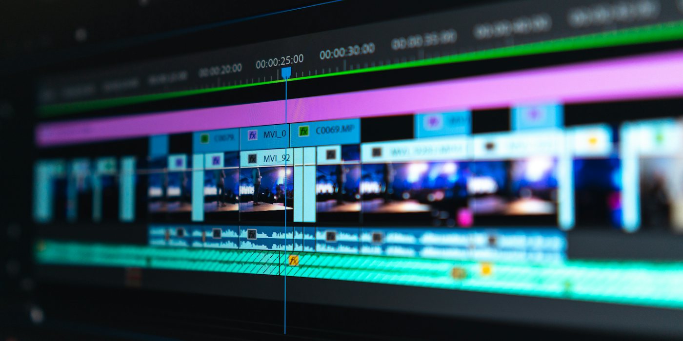 A video editing timeline with blue and purple clips on a dark screen