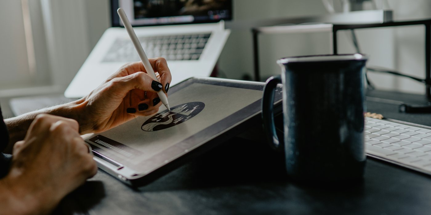 A person drawing on a tablet with a stylus at a desk