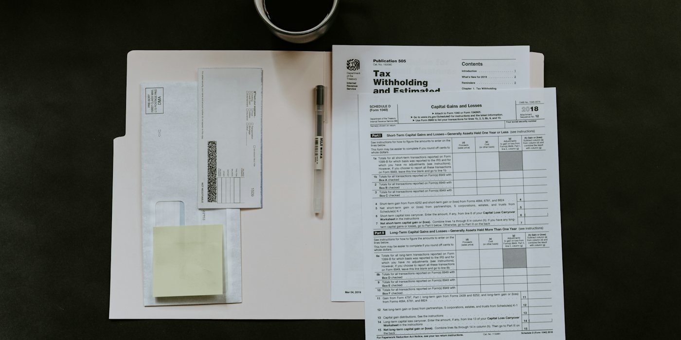 Tax forms, a pen, and a coffee mug on a dark desk