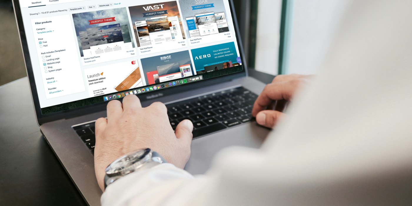 A person typing on a laptop showing a page of website thumbnails