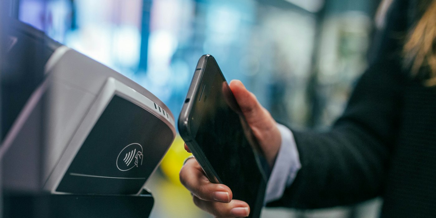 A customer holding a phone to a contactless card reader to pay